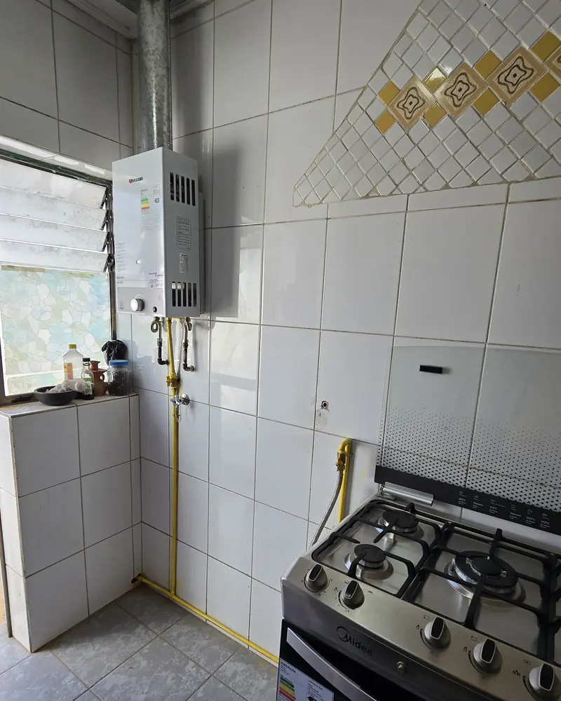 Cocina con un calefont en el muro, su ducto al exterior y una cocina a gas debajo
