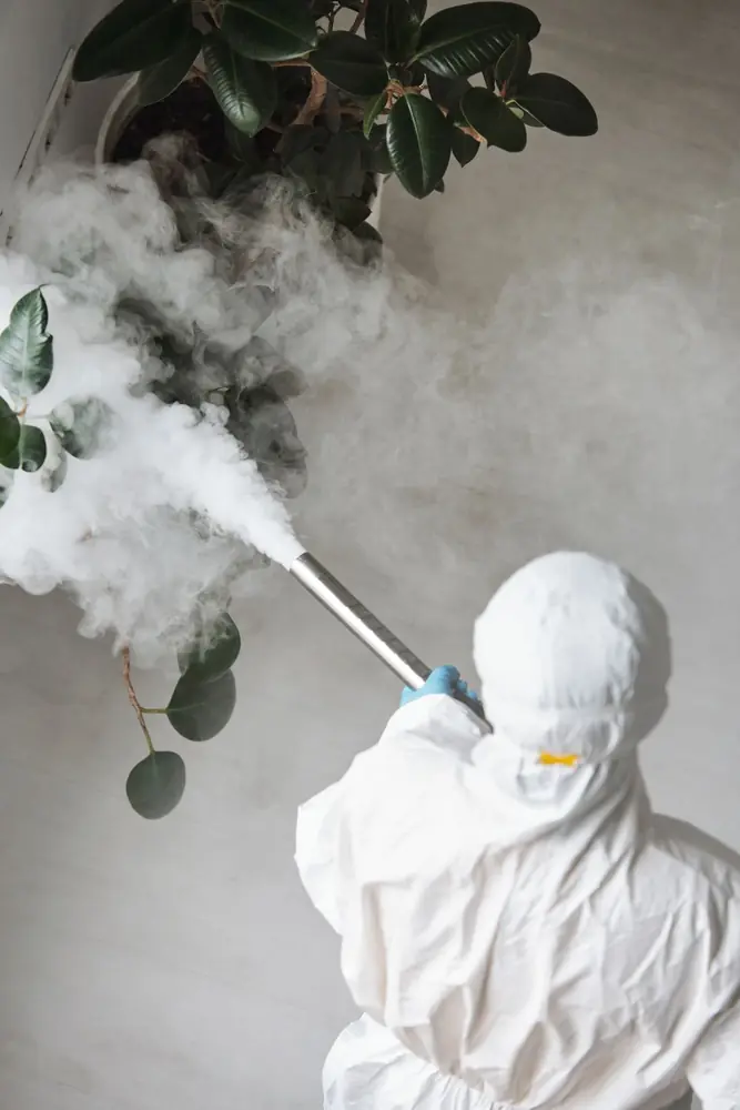Técnico con traje blanco de protección nebulizando un ambiente interior