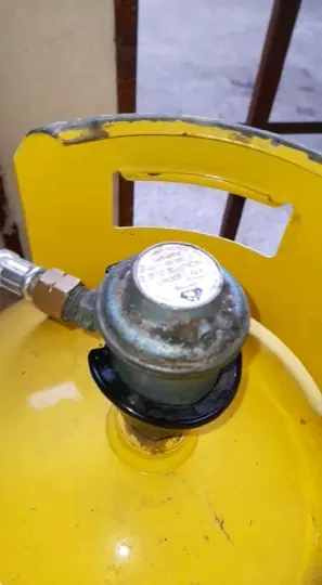 Regulador conectado a la válvula de un cilindro de gas amarillo