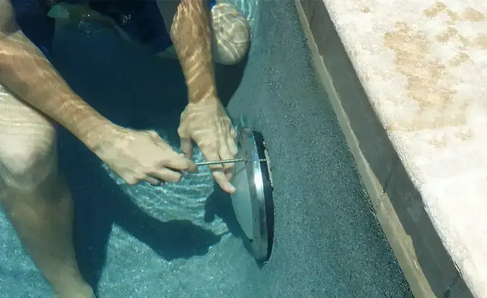 Técnico cambiando un foco dentro del agua de una piscina